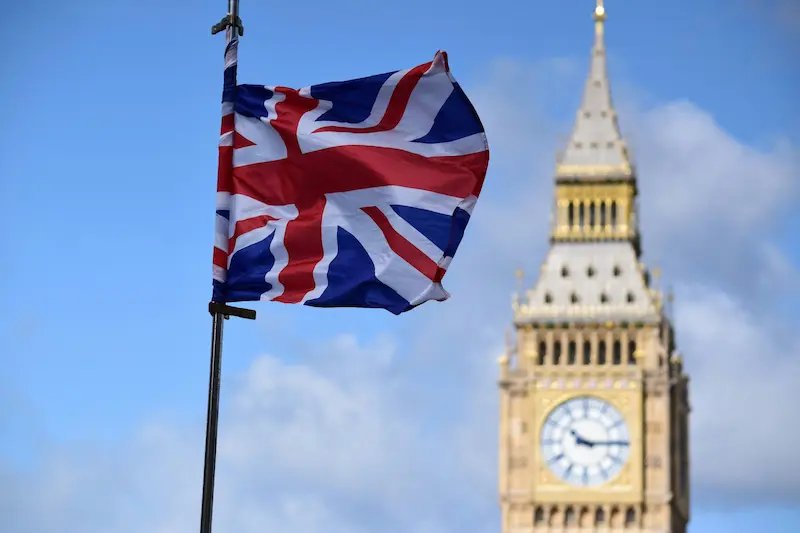 a flag on a pole with a clock tower in the background